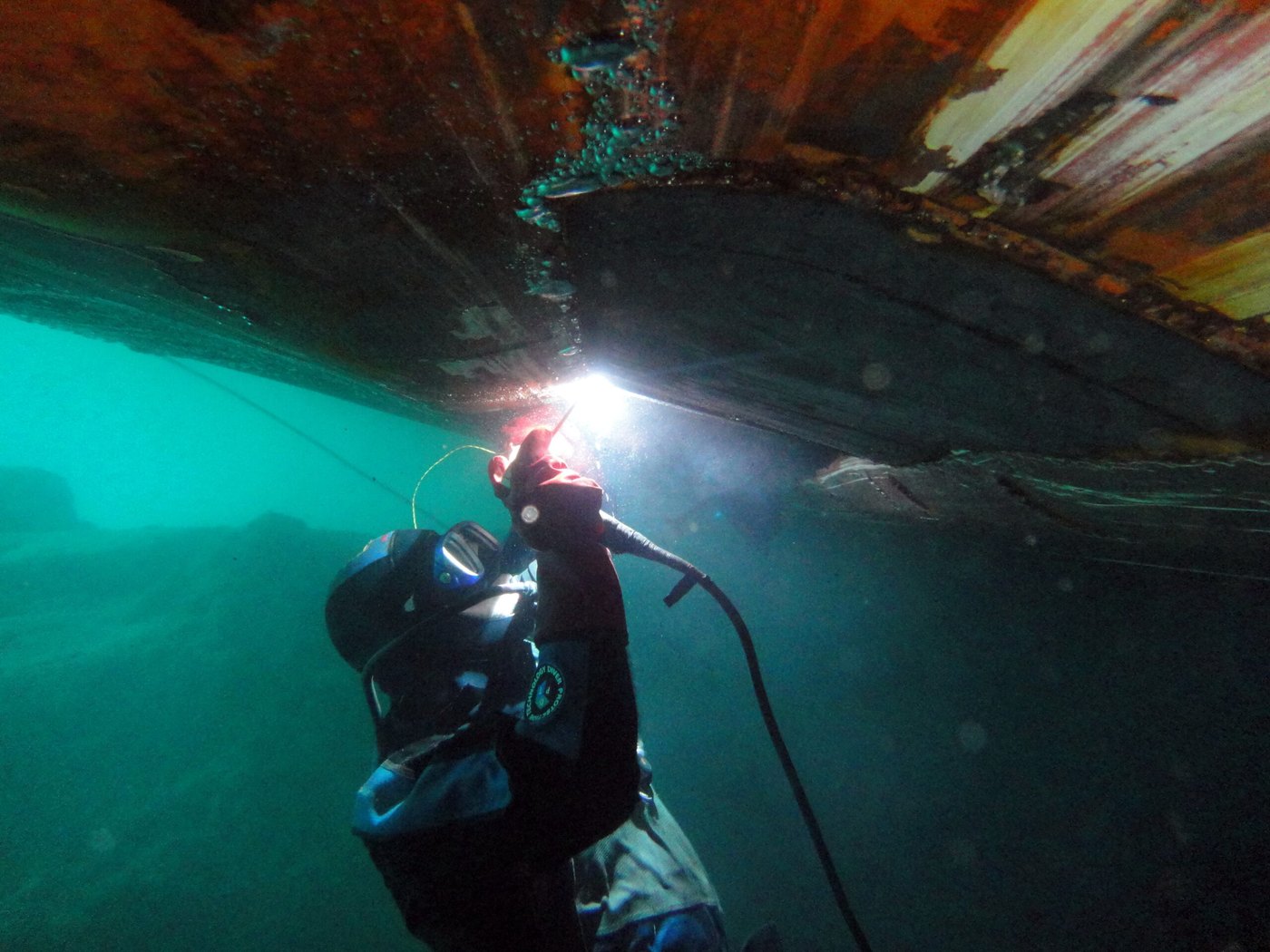 Commercial diver inspecting the hull of a vessel underwater at a Greek anchorage